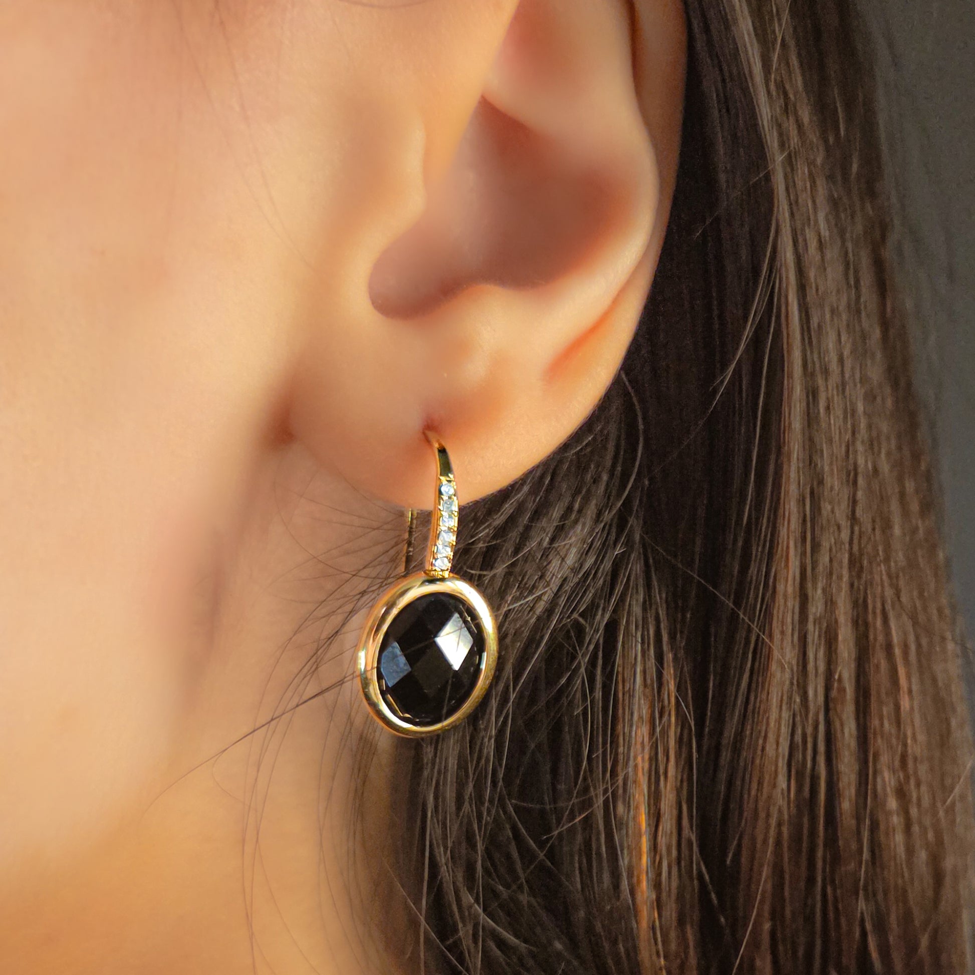 Boucles d’oreilles en acier inoxydable portées à l’oreille, ornées d’une pierre facettée et de petits éclats lumineux, bijou chic et raffiné.