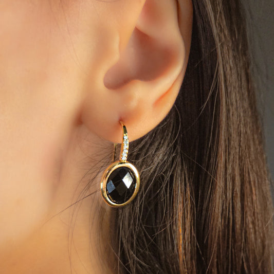 Boucles d’oreilles en acier inoxydable portées à l’oreille, ornées d’une pierre facettée et de petits éclats lumineux, bijou chic et raffiné.
