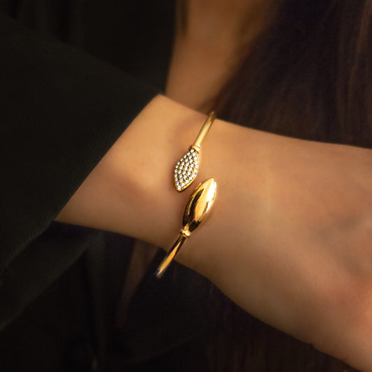 Bracelet ouvert en acier inoxydable porté au poignet, avec extrémité lisse et extrémité pavée brillante, bijou chic et raffiné.