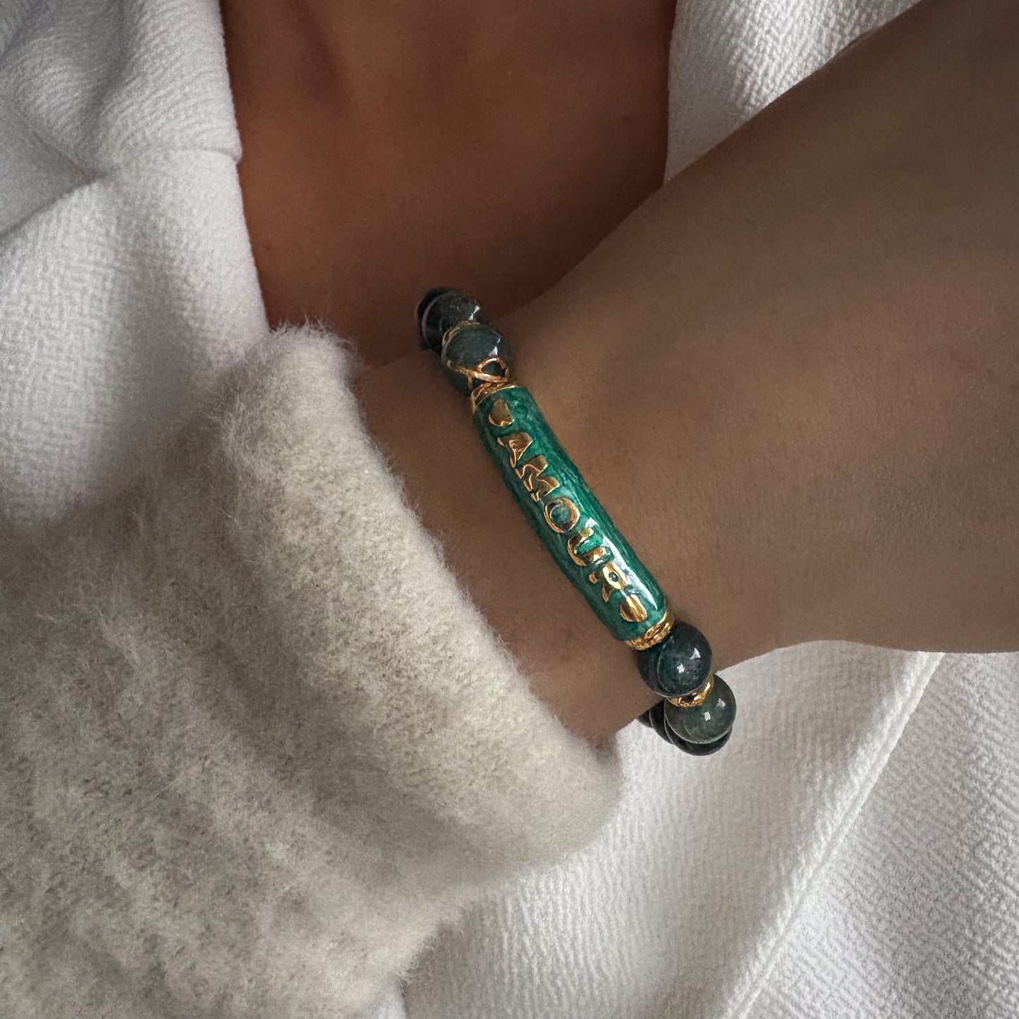 Bracelet en perles naturelles avec élément central gravé Amour, bijou symbolique porté au poignet.