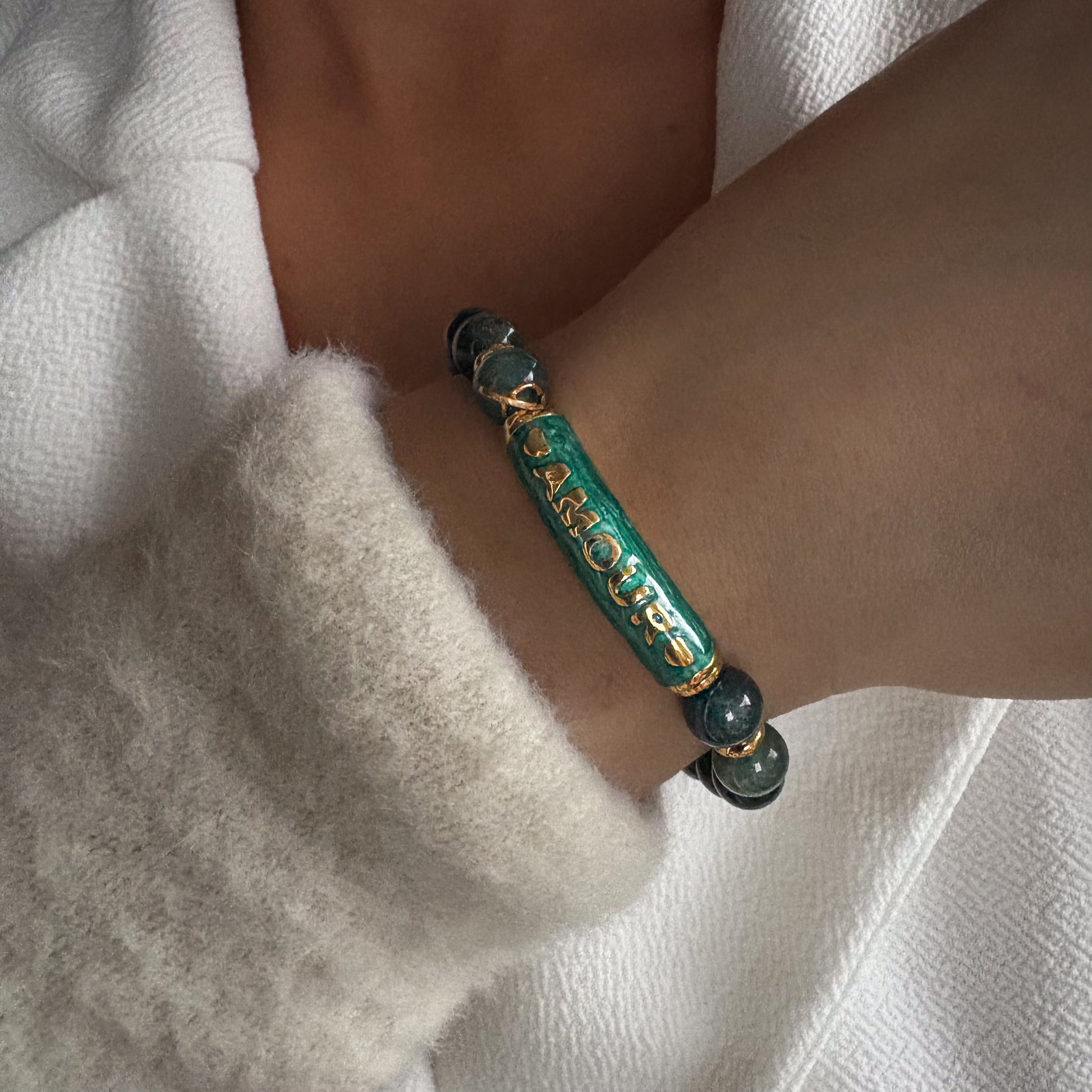 Bracelet en perles naturelles avec élément central gravé Amour, bijou symbolique porté au poignet.