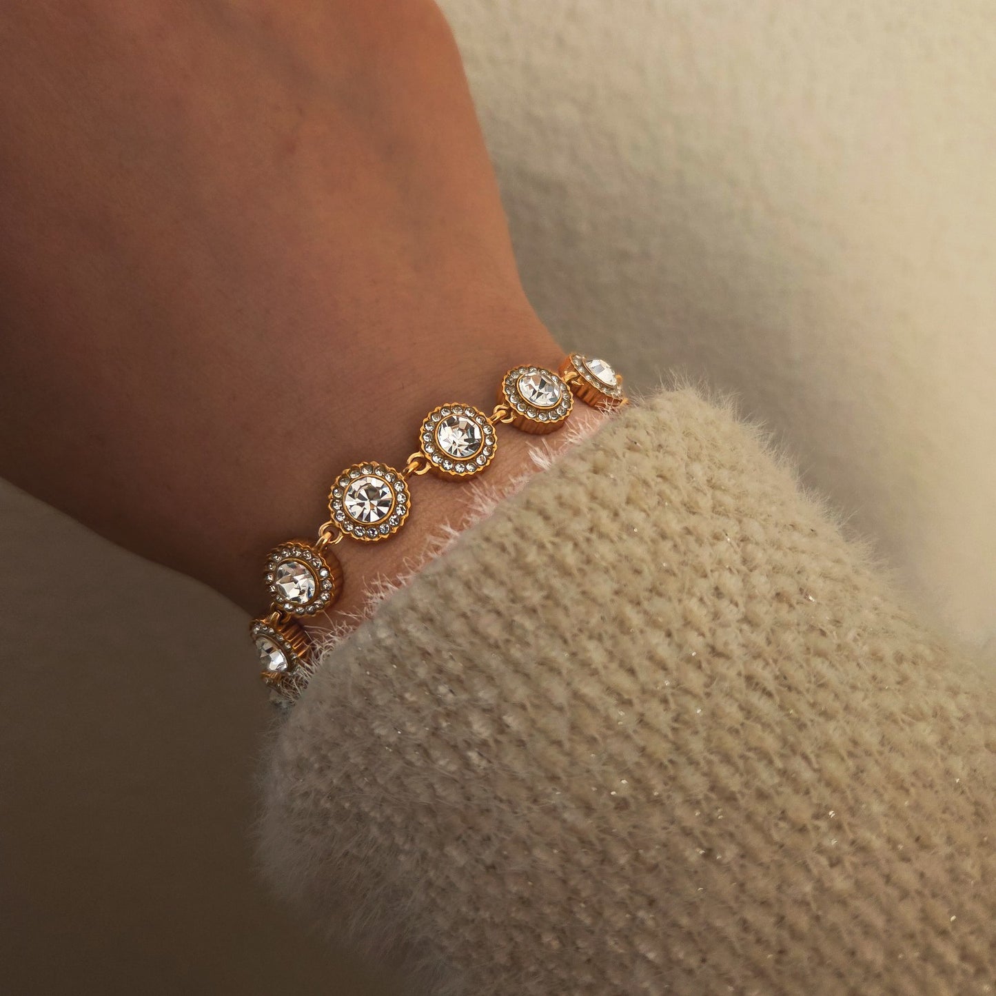 Bracelet doré à médaillons ronds sertis de strass porté