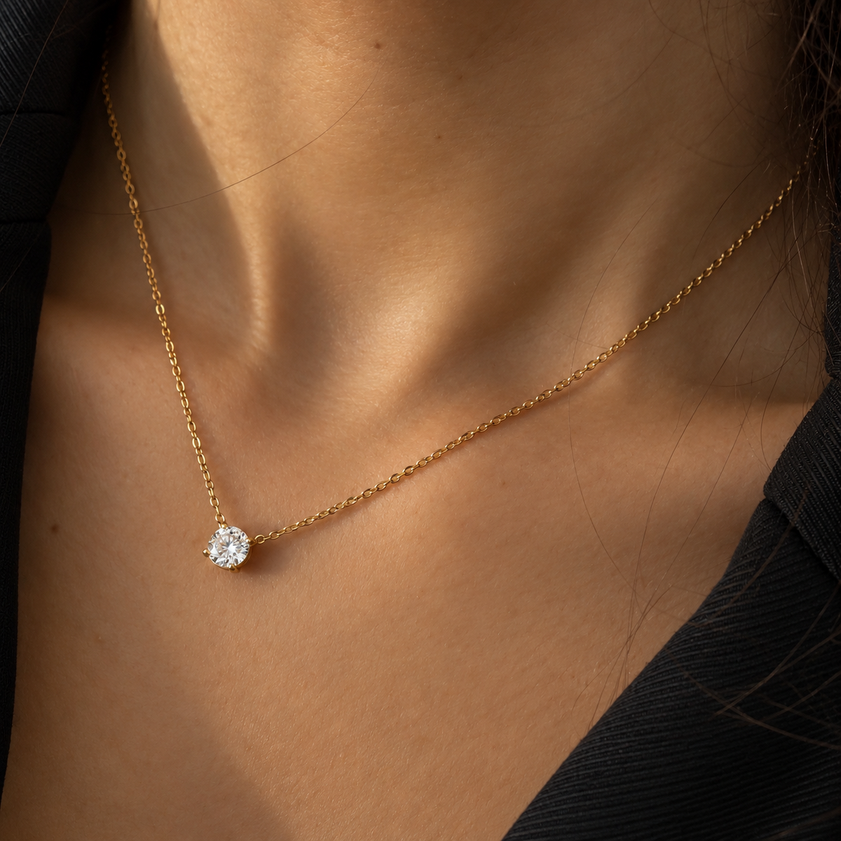 Collier doré à chaîne fine avec une pierre ronde transparente en solitaire, porté au cou