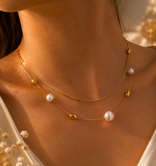 Collier double rang doré avec perles blanches et éléments dorés porté au cou