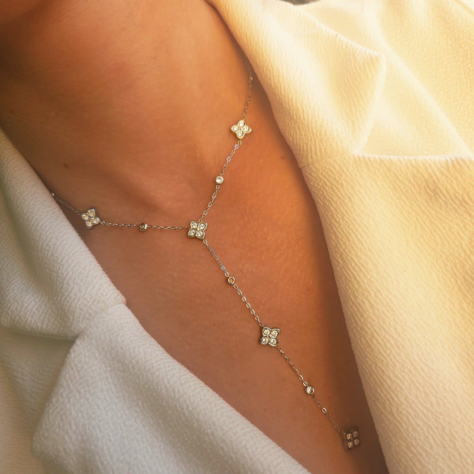 Collier argenté à fleurs serties de strass porté