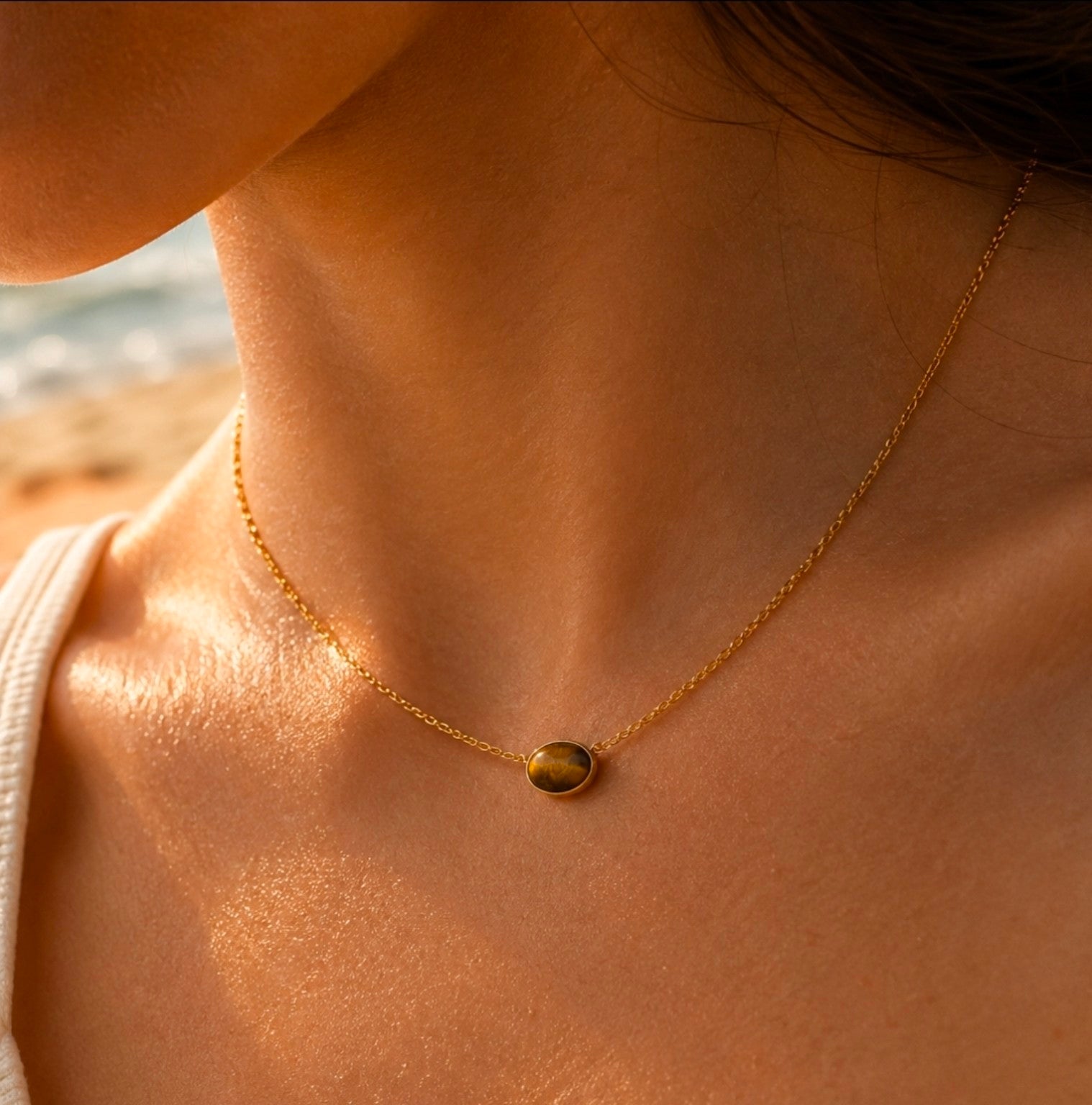 Collier doré fin avec pendentif rond brun effet œil-de-tigre porté au cou