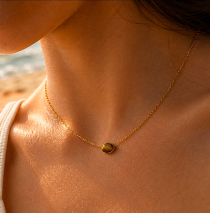 Collier doré fin avec pendentif rond brun effet œil-de-tigre porté au cou