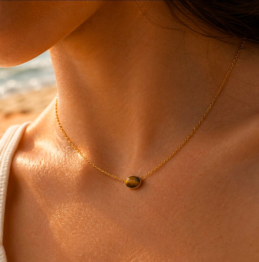 Collier doré fin avec pendentif rond brun effet œil-de-tigre porté au cou