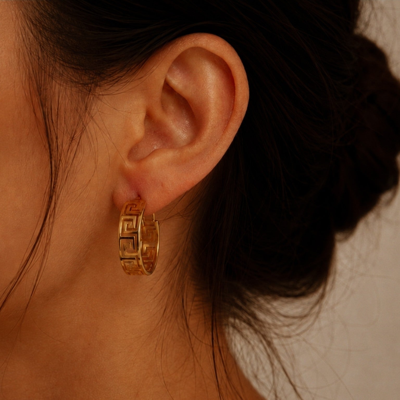 Créole dorée à motif géométrique, 3,2 cm de diamètre et 1 cm de largeur, portée à l’oreille