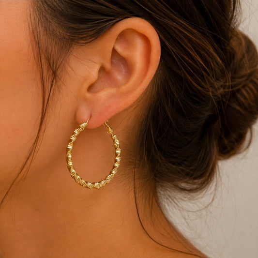 Créole dorée texturée en acier inoxydable portée à l’oreille