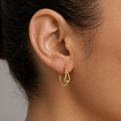 Créoles dorées effet corde avec détail nœud portées à l’oreille