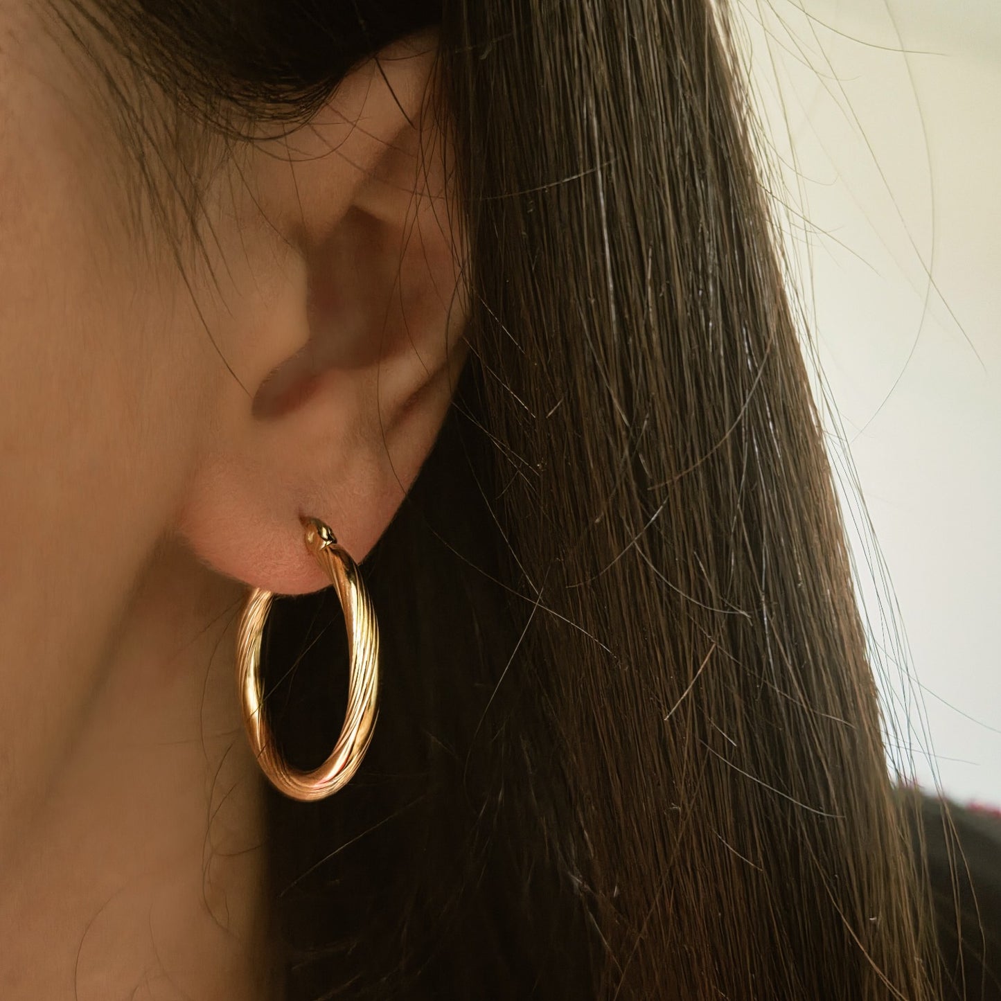 Boucles d’oreilles créoles torsadées en acier inoxydable portées