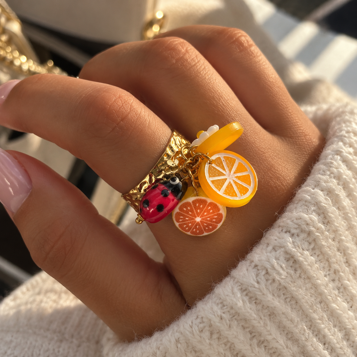 Bague fantaisie dorée à charms agrumes et coccinelle portée