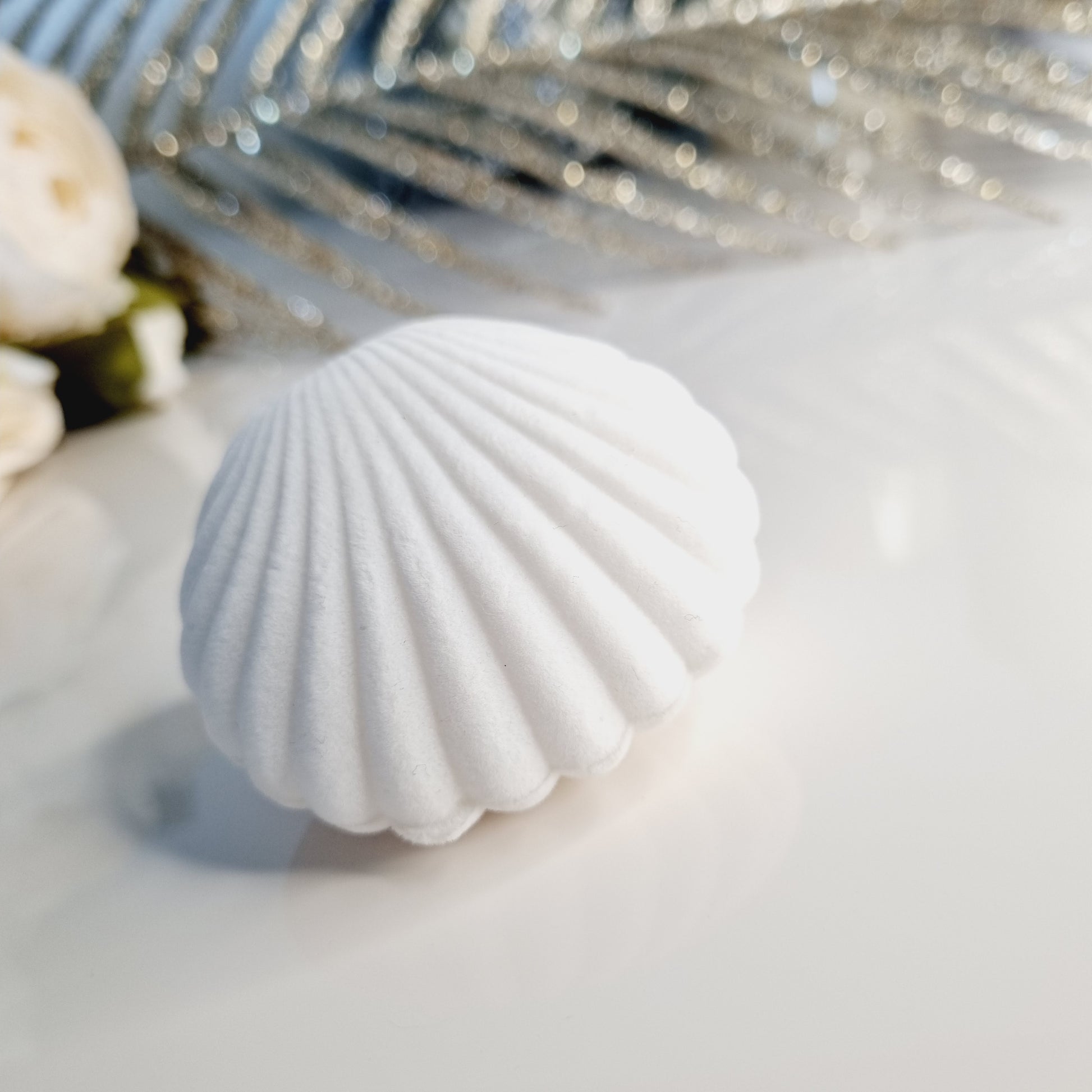 Photos du Coffret Bijoux Éclat Coquillage en forme de coquillage blanc, contenant des boucles d'oreilles blanches nacrées avec strass en forme de trèfle à 5 feuilles et une bague de phalange dorée et blanche de 16mm de diamètre intérieur.