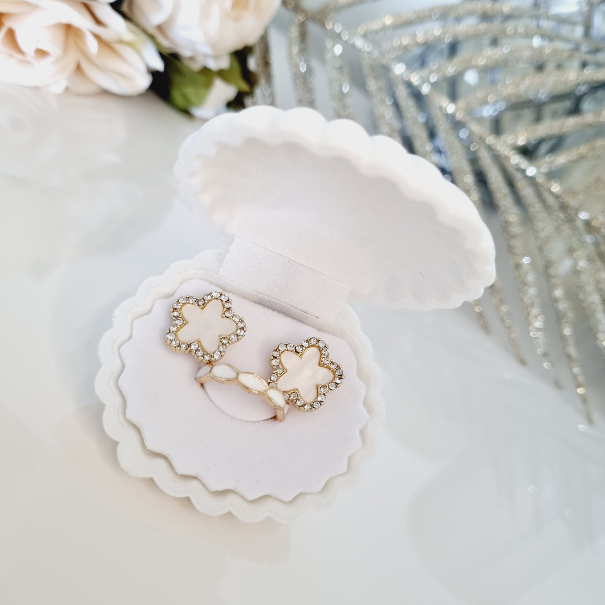 Photos du Coffret Bijoux Éclat Coquillage en forme de coquillage blanc, contenant des boucles d'oreilles blanches nacrées avec strass en forme de trèfle à 5 feuilles et une bague de phalange dorée et blanche de 16mm de diamètre intérieur.