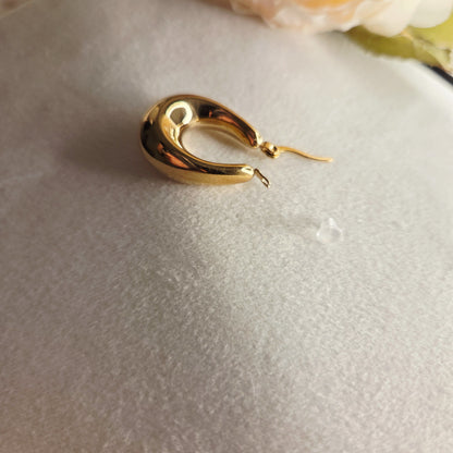 Boucles d’oreilles goutte dorées portées à l’oreille