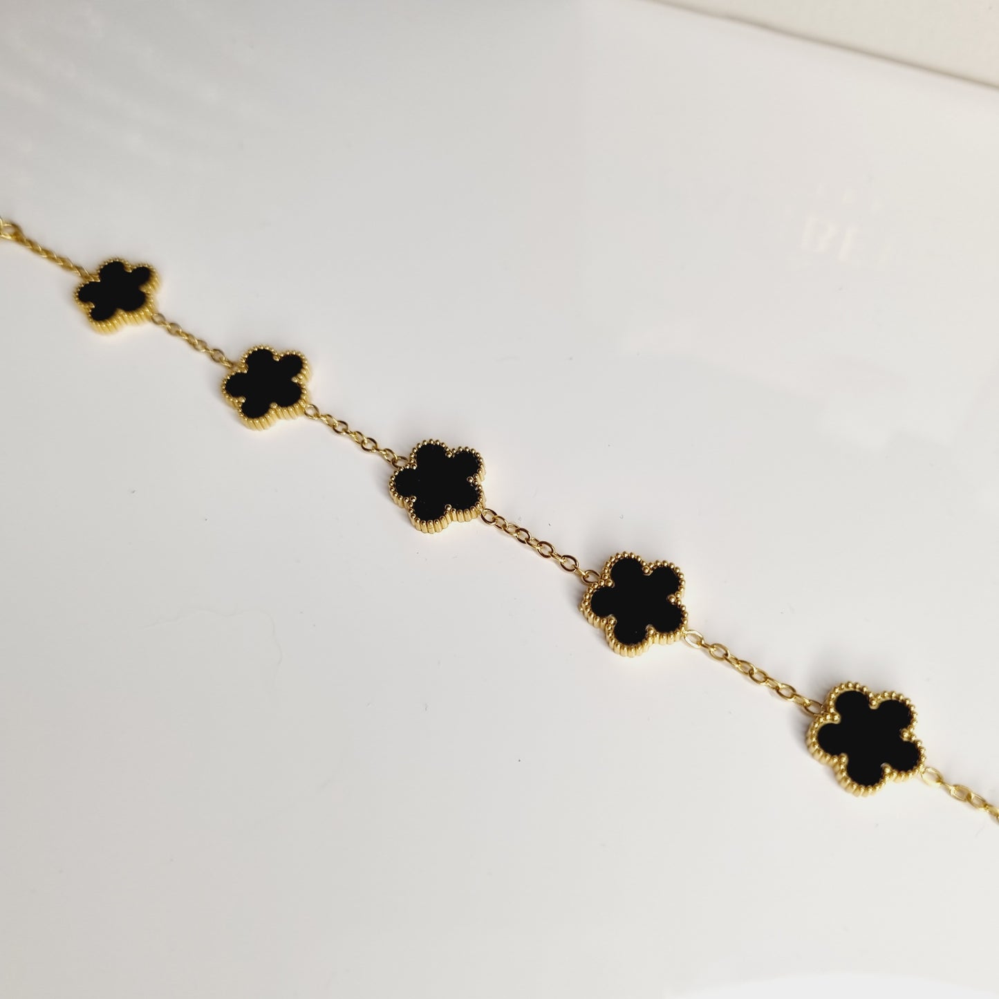 Photos du Bracelet Doré avec Pierres Noires en Forme de Trèfles à 5 Feuilles, en acier inoxydable plaqué or 18 carats. Bijou élégant et raffiné, parfait pour ajouter une touche de glamour à toutes vos tenues.