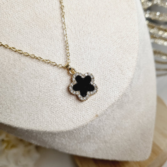 Collier doré avec pendentif en forme de fleur avec pierre noire ornée de strass scintillants. Chaîne ajustable