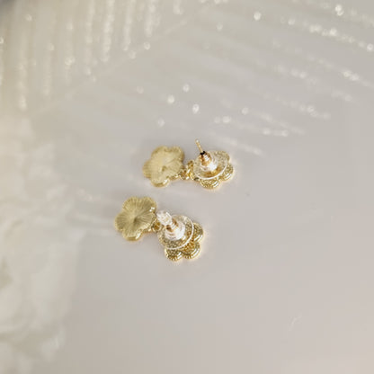 Boucles d’oreilles Estella dorées portées, motif trèfle pendant