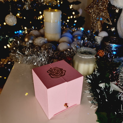 Boîte cadeau, vue fermée, couleur rose; avec jolie rose dorée comme motif. Pour offrir à une femme. Cadeau réussi, qui suscitera beaucoup d'émotions garanti.